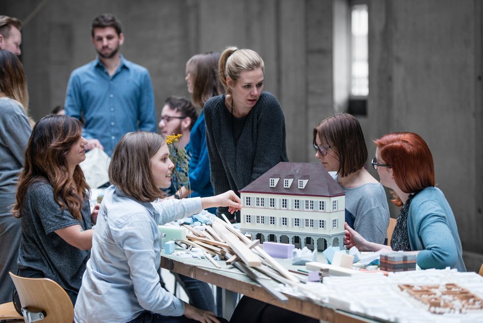 Mehrere Studierende sitzen am Tisch und bauen Modelle